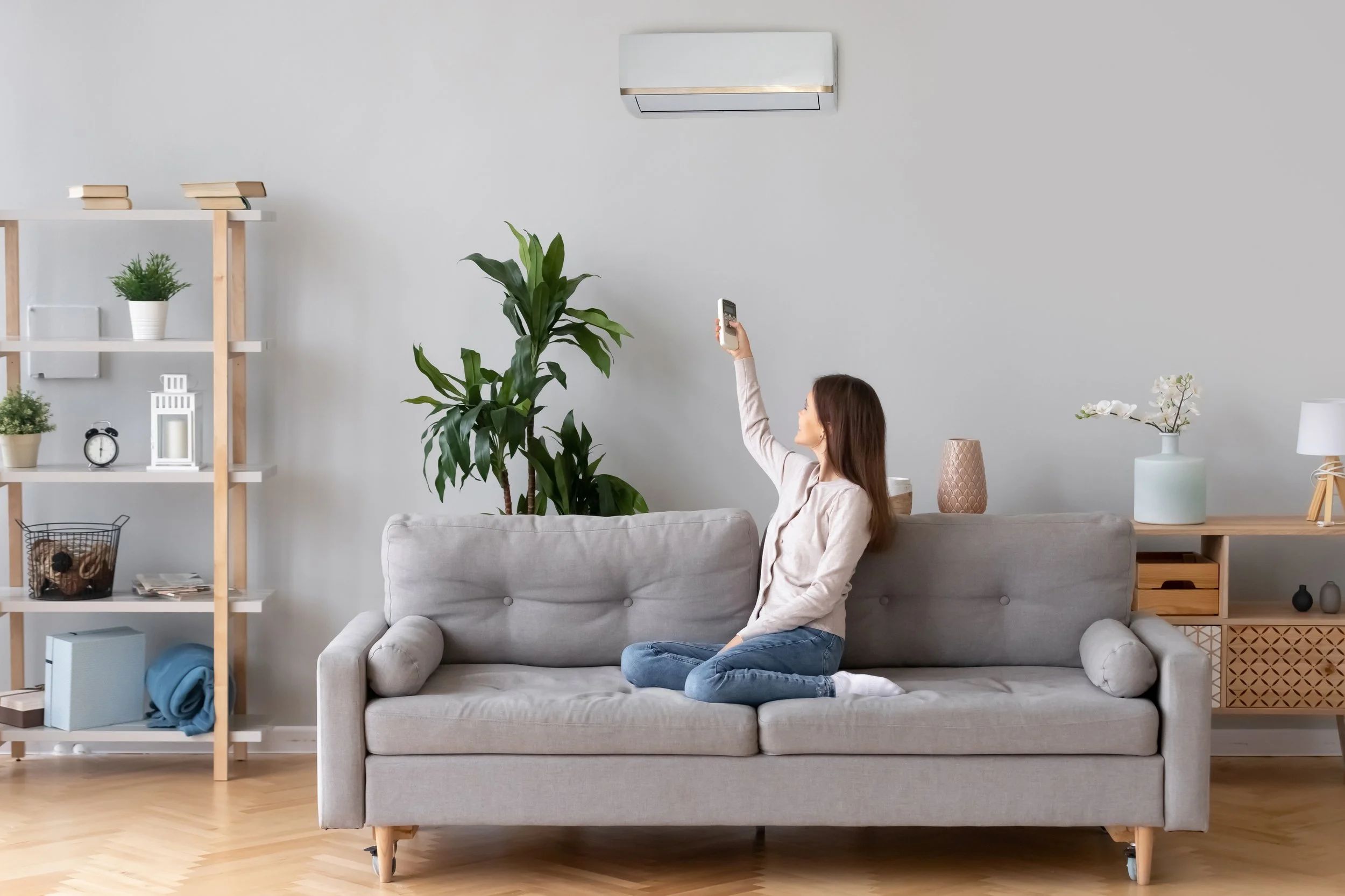 Woman adjusting her ductless mini-split with a remote